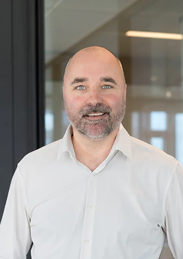 Bald white man with drak beard in a white shirt